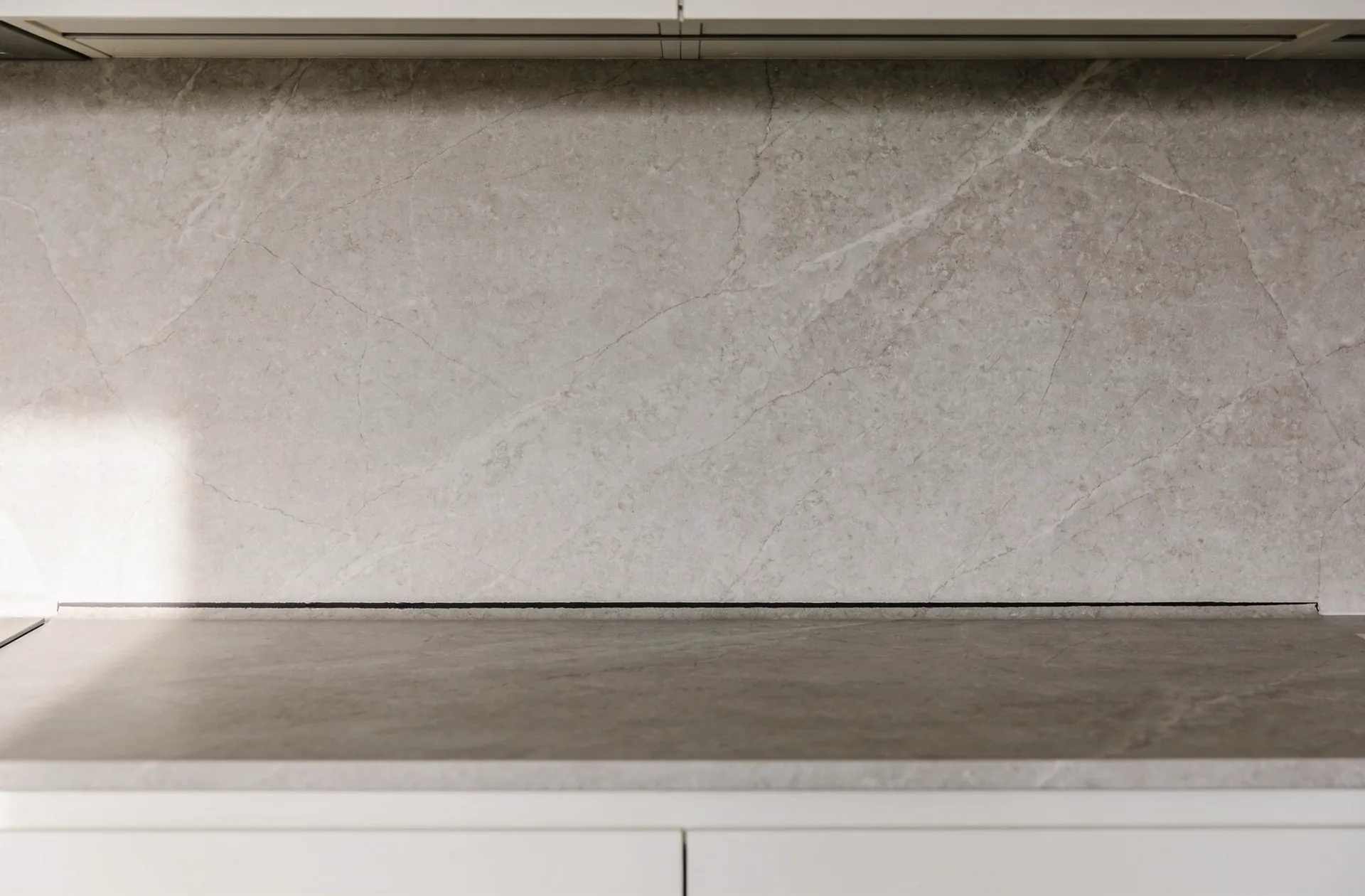 A stone splashback meeting the benchtop with the junction left unsealed